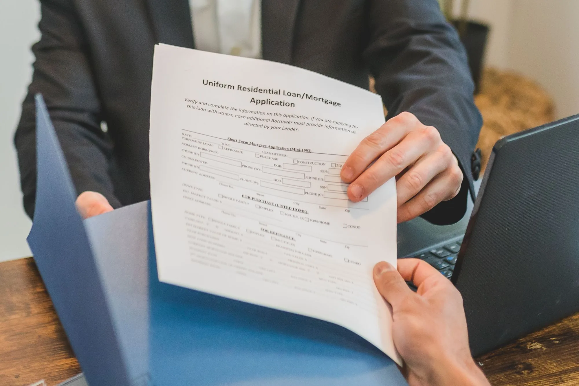 Een hypotheekaanvraag wordt over een tafel doorgegeven tijdens een adviesgesprek